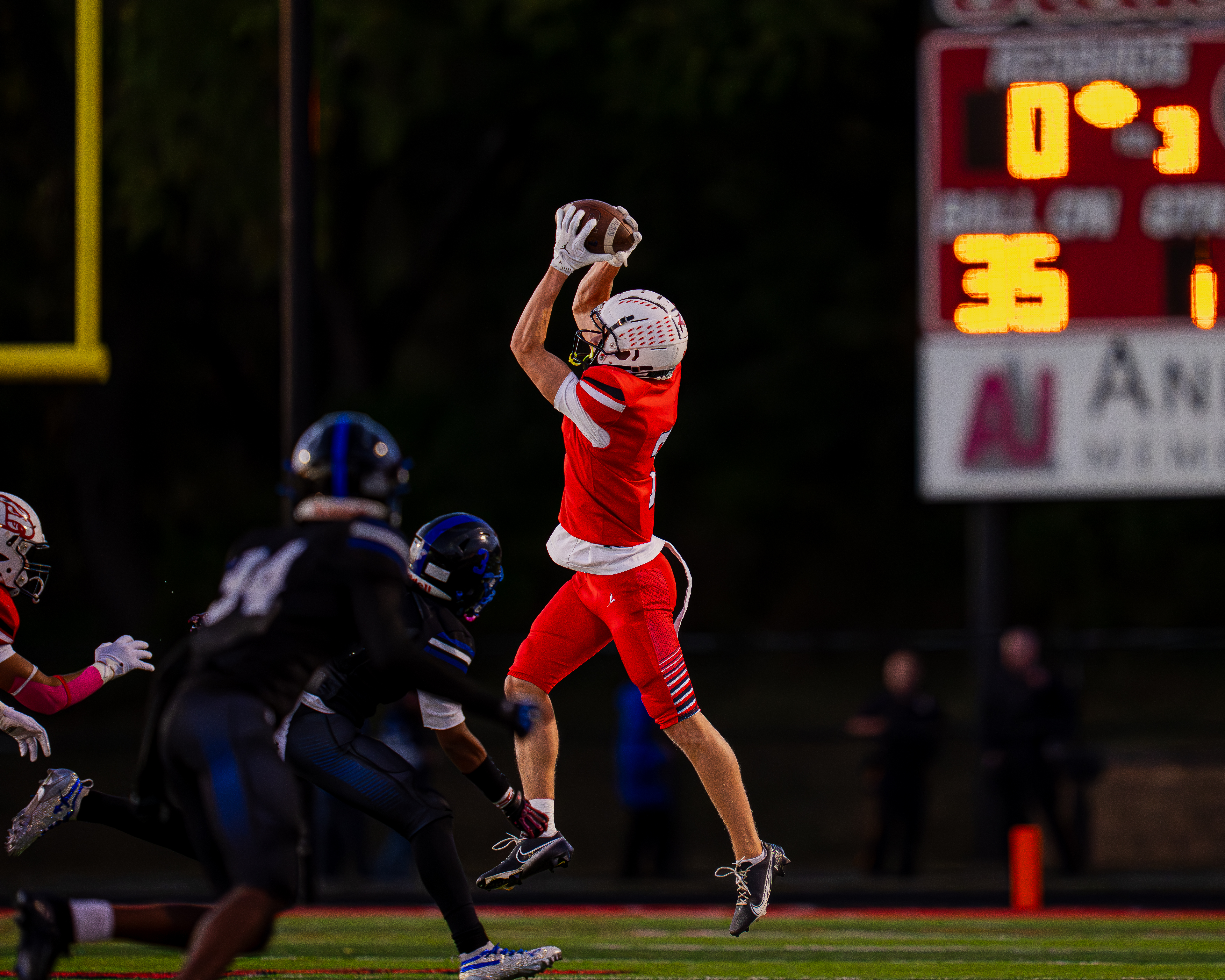 Receiver hauling in a touchdown under the lights